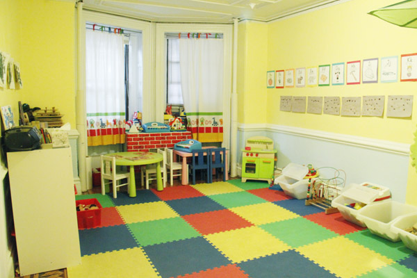 Archival photo of the daycare playroom with colorful floor mats and play materials
